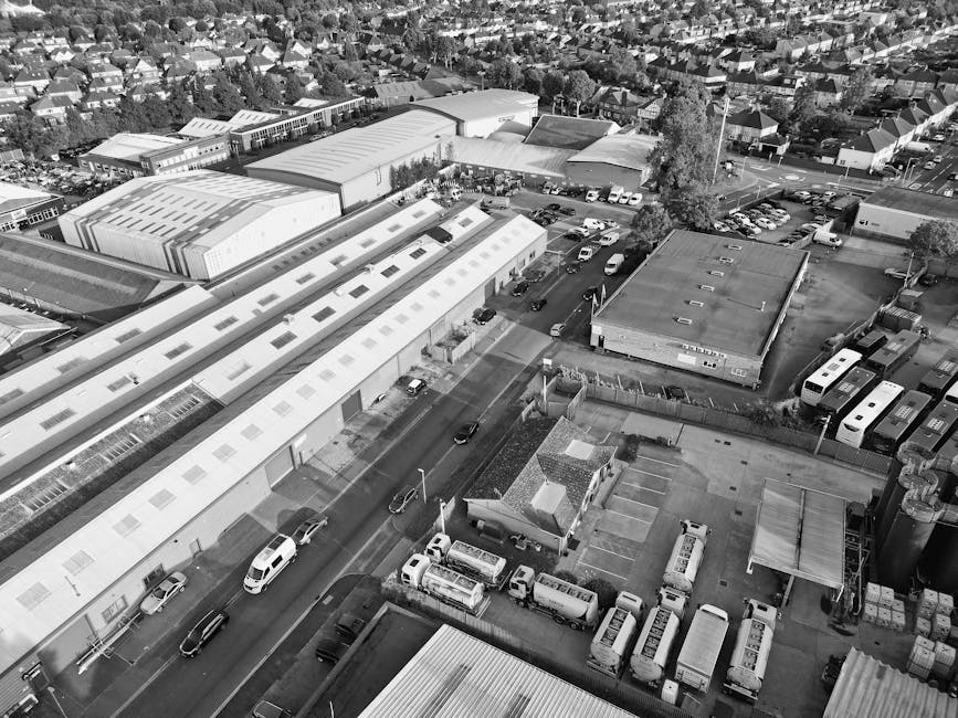 A high-angle view of a busy street in East Finchley showing parked and moving vehicles, including a white van and several cars, along a curved road with pedestrian crossings and sidewalks. Trees line 